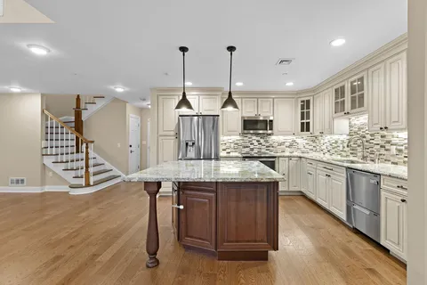 a kitchen with kitchen island granite countertop a sink cabinets and wooden floor