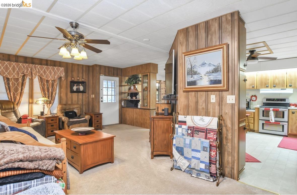 4603 Balfour Road, Unit 86 Brentwood, CA 94513 - Photo 7 of 24 Living area featuring a ceiling fan, wooden walls, and light colored carpet