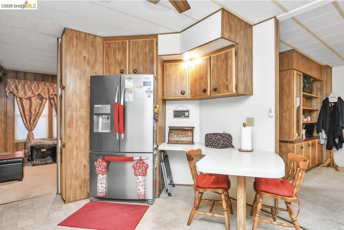 4603 Balfour Road, Unit 86 Brentwood, CA 94513 - Photo 8 of 24 Kitchen featuring stainless steel fridge with ice dispenser, light countertops, brown cabinets, a breakfast bar area, and light flooring