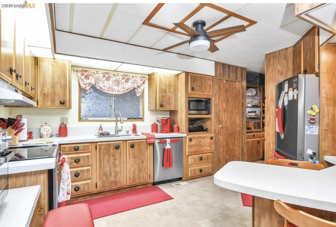 4603 Balfour Road, Unit 86 Brentwood, CA 94513 - Photo 9 of 24 Kitchen featuring light countertops, appliances with stainless steel finishes, light floors, and brown cabinets