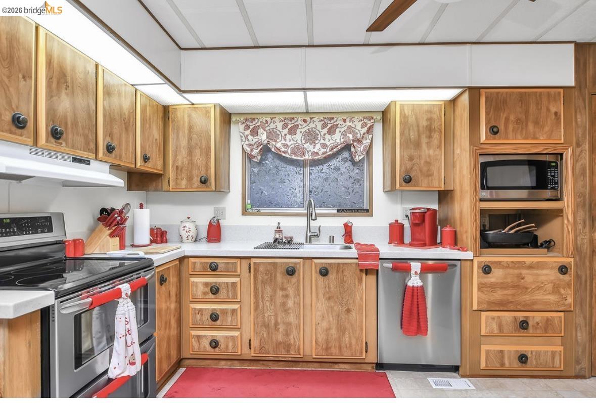 4603 Balfour Road, Unit 86 Brentwood, CA 94513 - Photo 10 of 24 Kitchen with appliances with stainless steel finishes, light countertops, under cabinet range hood, and brown cabinetry