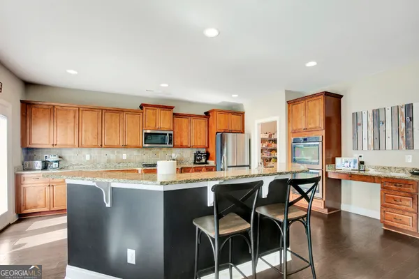 a kitchen with stainless steel appliances granite countertop a refrigerator a stove a sink dishwasher and white cabinets with wooden floor