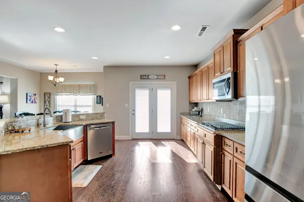 a kitchen with stainless steel appliances granite countertop a refrigerator a sink dishwasher and white cabinets with wooden floor