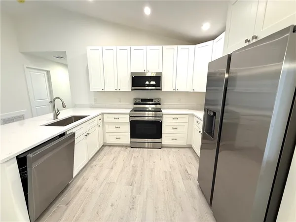 a kitchen with a sink a refrigerator a microwave and cabinets
