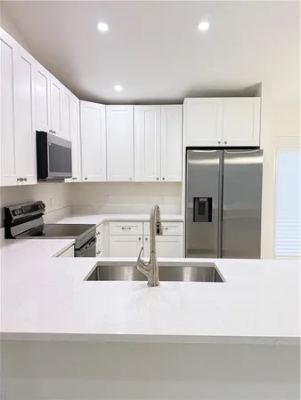 a kitchen with stainless steel appliances granite countertop a refrigerator a stove and a sink with wooden floor