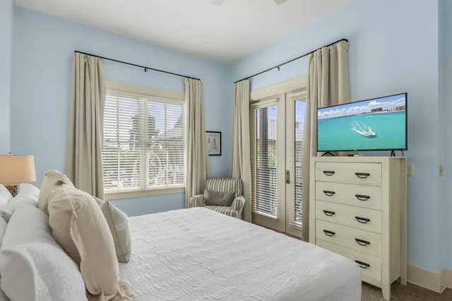 a bedroom with a bed and a flat tv screen next to a window