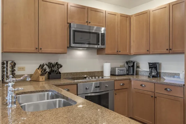 a kitchen with stainless steel appliances granite countertop a sink a stove and a microwave with granite countertops