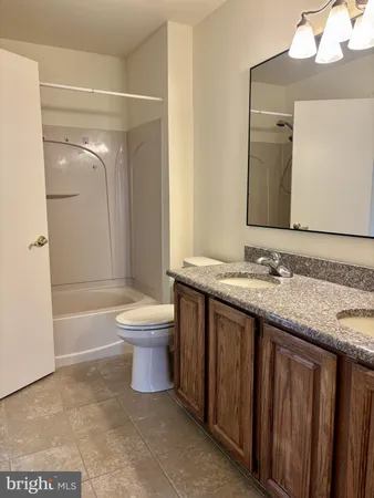 a bathroom with a granite countertop sink toilet a mirror and bathtub