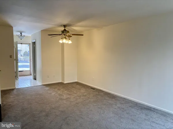 an empty room with a chandelier fan and a bathroom
