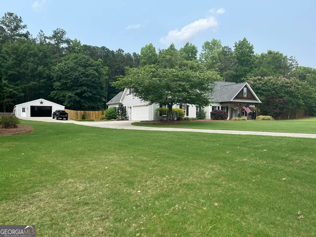 a view of a house with a big yard and large trees