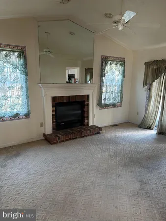 an empty room with windows fireplace and fan
