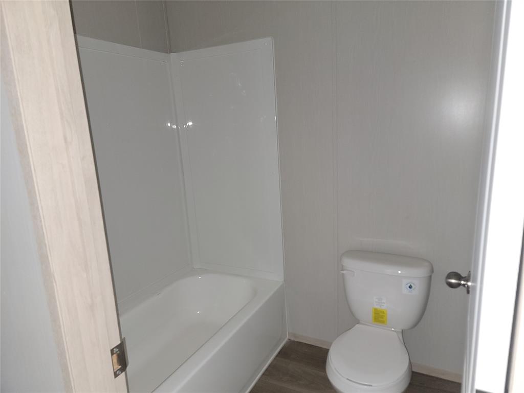387 Duvall Street Bonham, TX 75418 - Photo 22 of 24 a white toilet sitting next to a bathtub