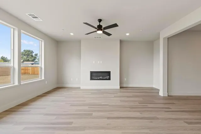 a view of an empty room with a window and kitchen view