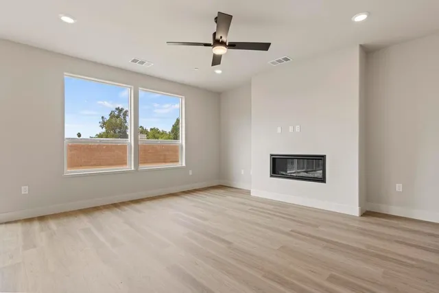a view of an empty room with a window and wooden floor