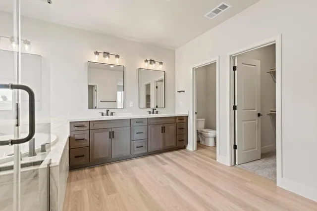 a spacious bathroom with a double vanity sink a mirror a bathtub and shower
