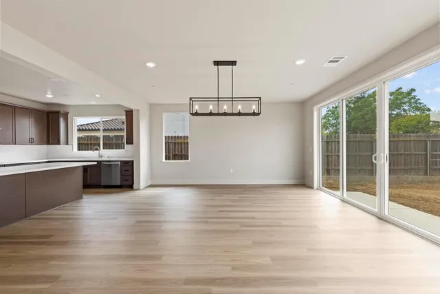 a view of an empty room with kitchen and window