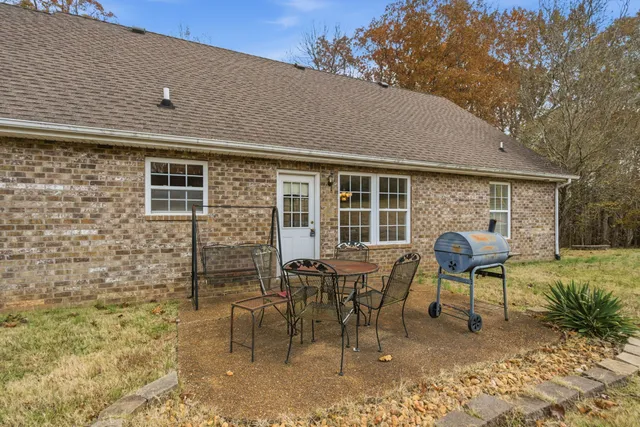 a outdoor dining room with furniture a chandelier and a window