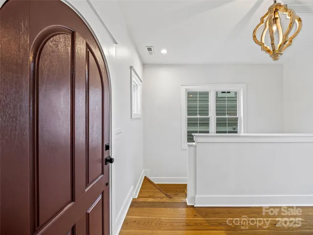 a view of an empty room with wooden floor and stairs