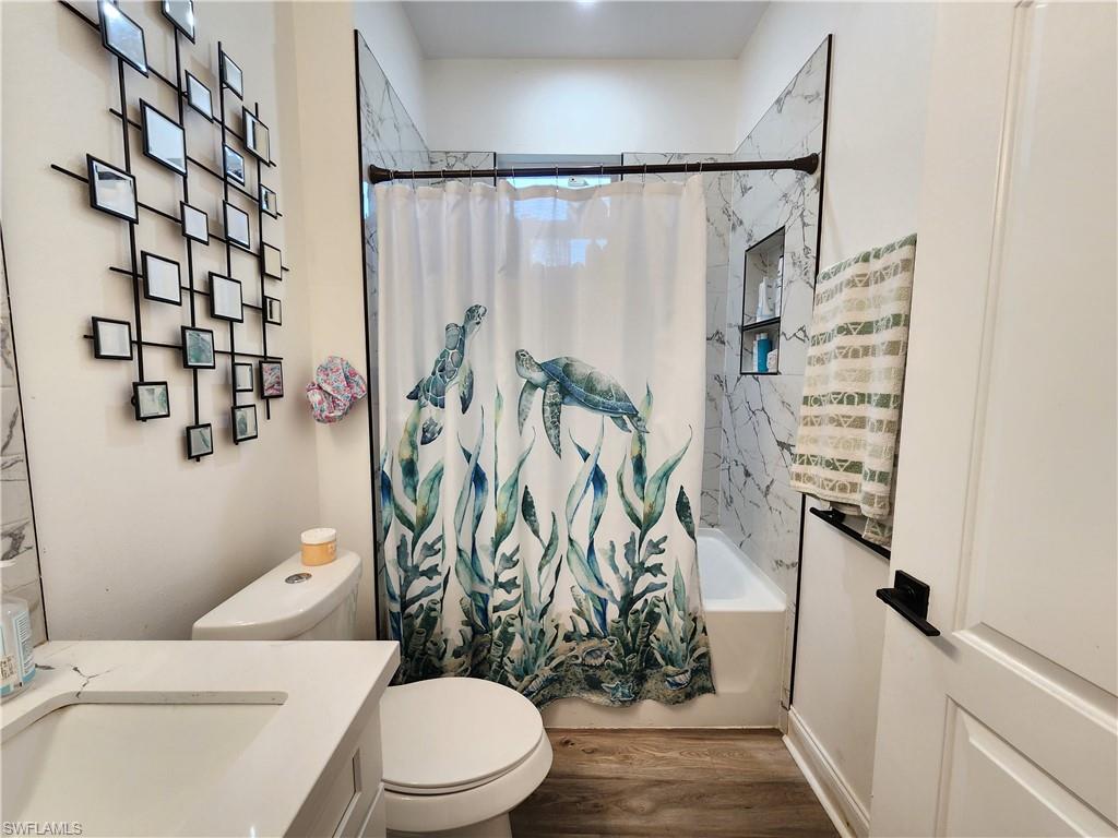4045 34th Avenue Southeast Naples, FL 34117 - Photo 14 of 30 Bathroom featuring vanity, shower / bath combo with shower curtain, and wood finished floors