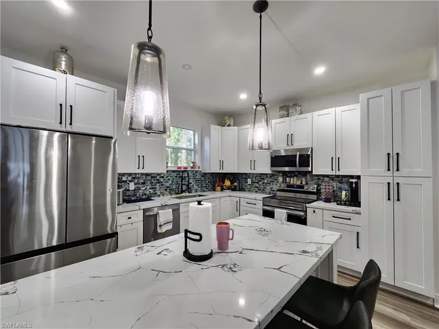 a kitchen with stainless steel appliances kitchen island granite countertop a refrigerator a stove a sink a dining table and chairs