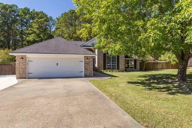a view of a house with a yard and a large tree