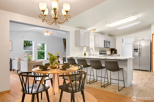 a kitchen with kitchen island granite countertop a dining table chairs and a refrigerator