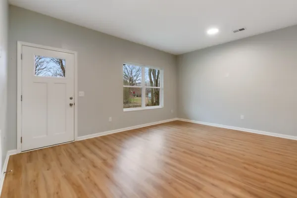 an empty room with wooden floor and windows