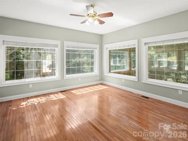 a view of an empty room with a window and wooden floor