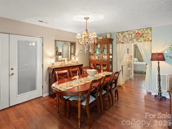 a dining room with wooden floor a chandelier a wooden table and chairs