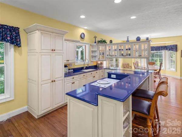 a kitchen with stainless steel appliances granite countertop a refrigerator a sink dishwasher a dining table and chairs with wooden floor