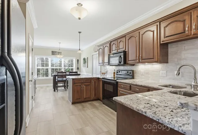 a kitchen with stainless steel appliances granite countertop a stove top oven a sink dishwasher a dining table and chairs with wooden floor