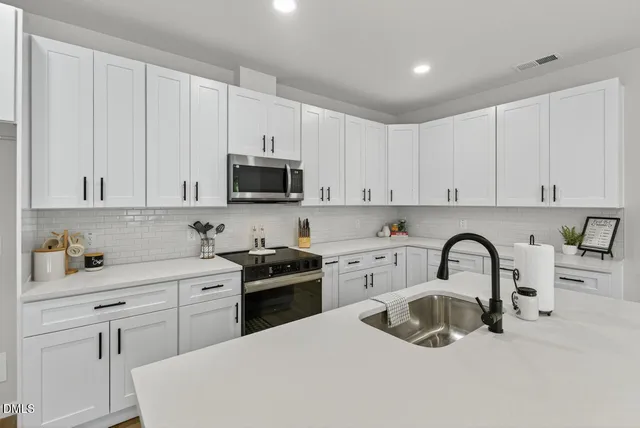 a kitchen with a sink a stove a refrigerator cabinets and dining table