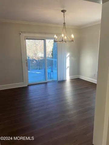 a view of a room with wooden floor chandeliers and kitchen view