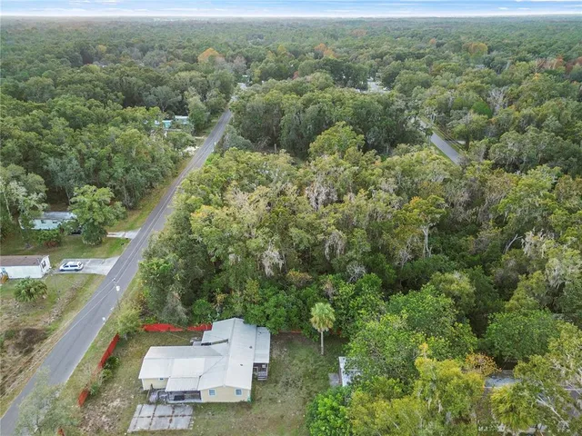 an aerial view of a residential houses with a lush green forest