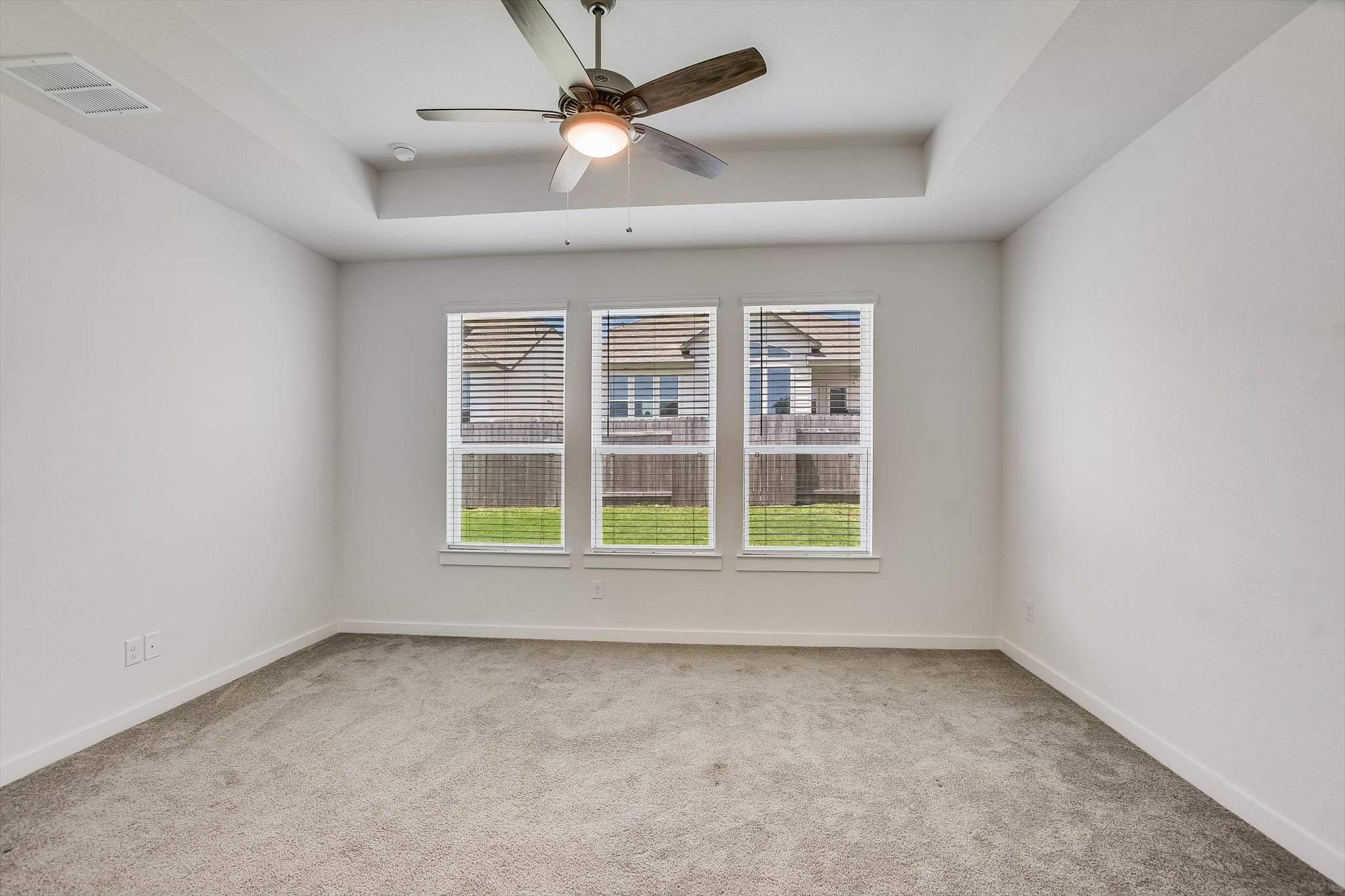 205 Wingstem Way Georgetown, TX 78633 - Photo 13 of 29 Spacious Primary bedroom featuring a tray ceiling, ceiling fan with integrated lighting, three large windows, textured carpeting, and white baseboards