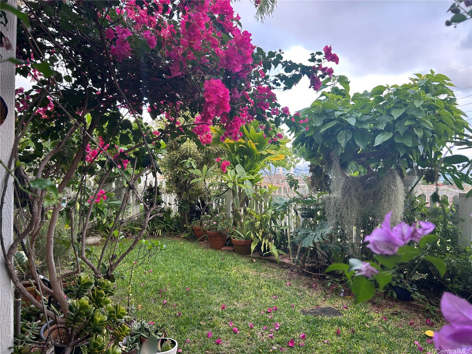 94-510 Lumiaina Street, Unit M103 Waipahu, HI 96797 - Photo 2 of 24 a small yard with fountain and flowers