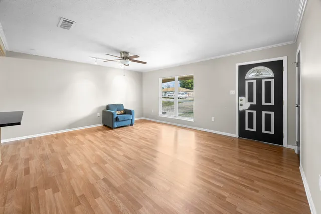 a view of empty room with wooden floor and fan