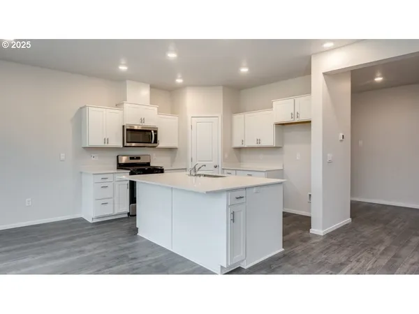 a kitchen with stainless steel appliances a sink a stove a microwave a sink and cabinets