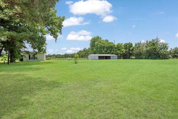 a view of a grassy field with trees