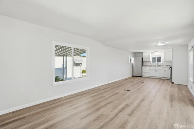 a view of an empty room with a kitchen and a window