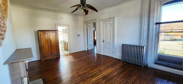a view of empty room with wooden floor and fan