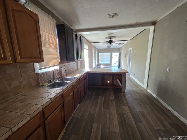 a kitchen with granite countertop a sink cabinets and wooden floor