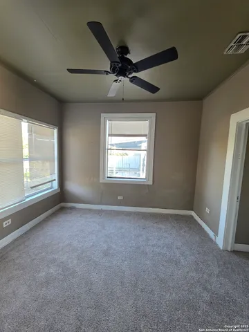 an empty room with windows and fan