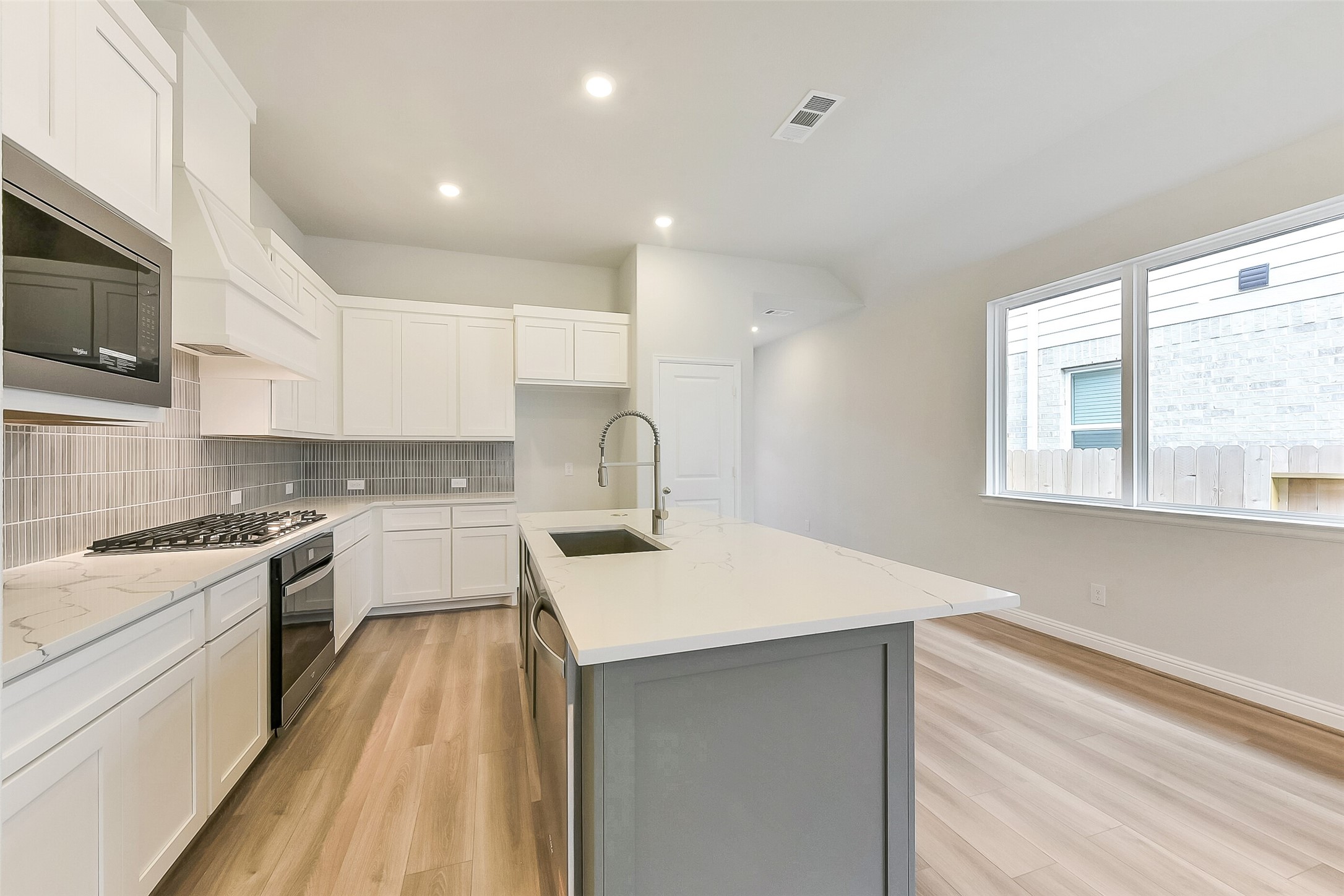 16323 Placid Stream Street Conroe, TX 77302 - Photo 13 of 36 a kitchen with a sink a stove top oven and white cabinets