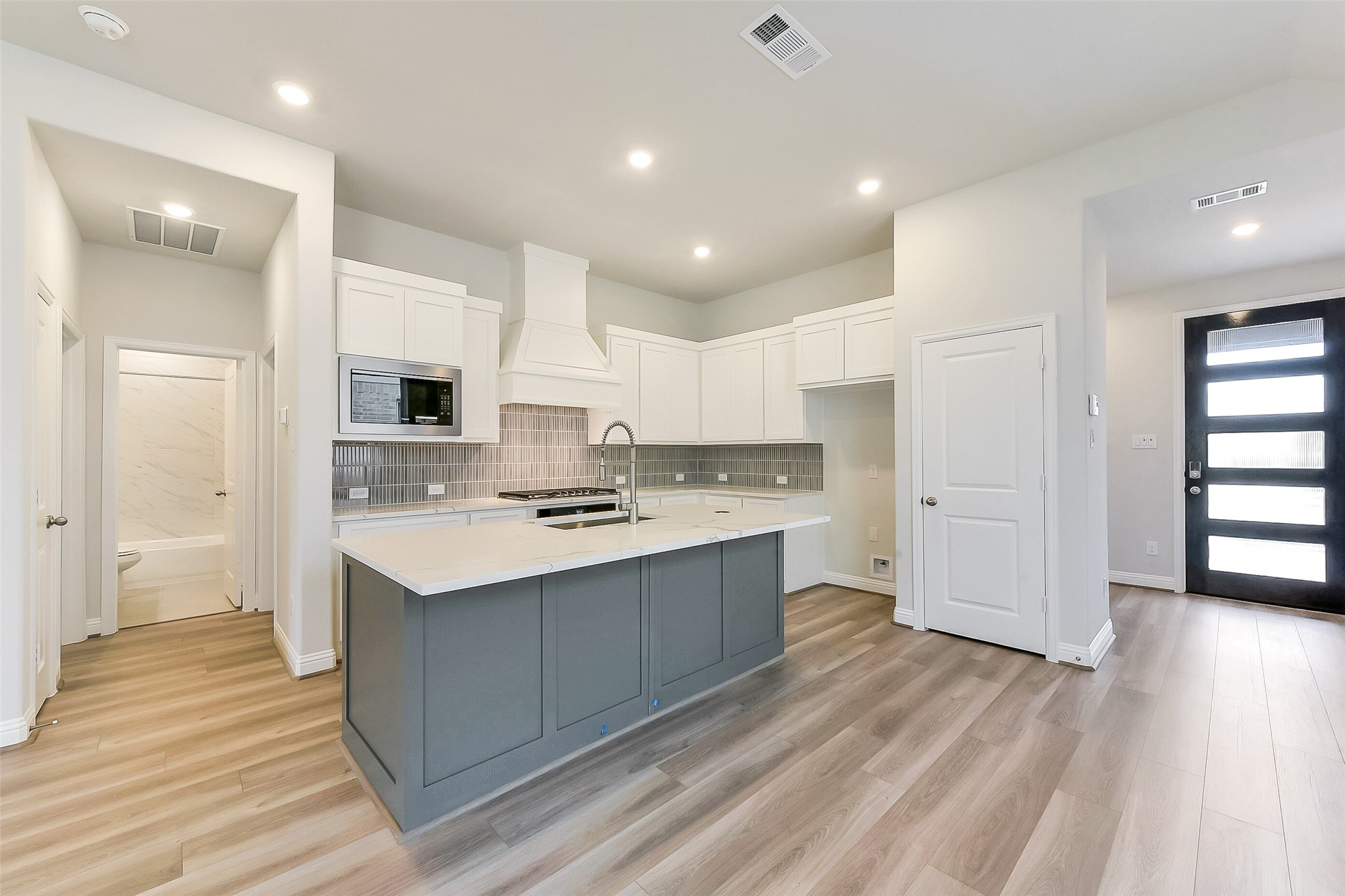 16323 Placid Stream Street Conroe, TX 77302 - Photo 10 of 36 a kitchen with stainless steel appliances kitchen island hardwood floor sink and stove