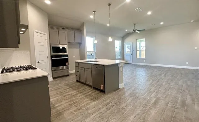 a room with kitchen island a sink appliances and cabinets
