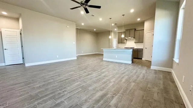 a view of an empty room with a window and wooden floor