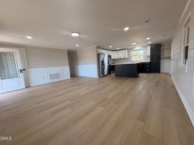 a view of a big room with wooden floor and windows