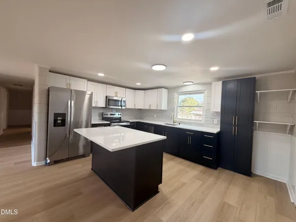 a kitchen with stainless steel appliances granite countertop a sink stove refrigerator and cabinets