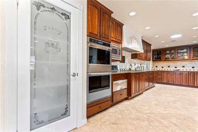 a kitchen with stainless steel appliances granite countertop a refrigerator a stove and a sink with wooden cabinets